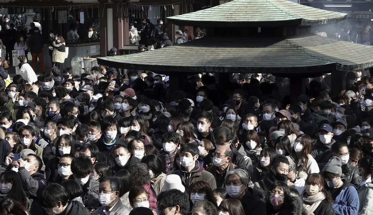 Pengunjung menunggu untuk berdoa memohon keberuntungan selama "hatsumode", atau kunjungan pertama mereka tahun ini ke kuil atau kuil, di kuil Buddha Kawasaki Daishi di Kawasaki, dekat Tokyo, Senin (3/1/2022). (AP Photo/Eugene Hoshiko)