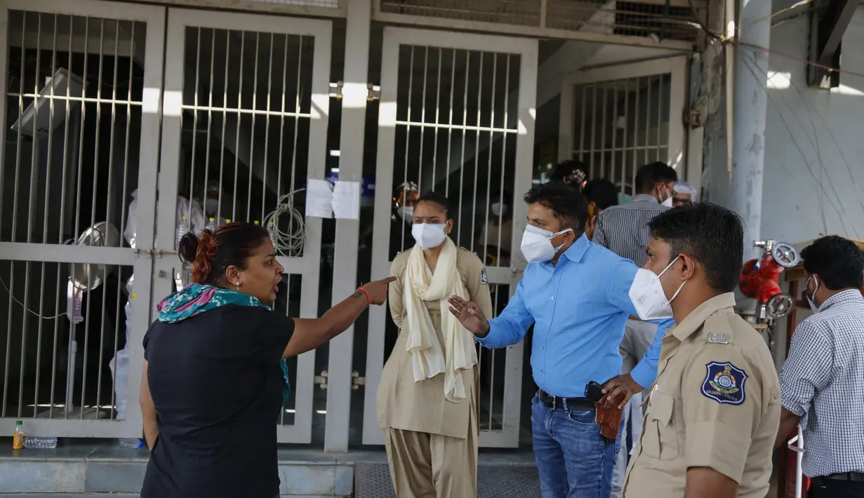 Seorang kerabat pasien berdebat dengan petugas polisi di luar rumah sakit pemerintah khusus COVID-19 di Ahmedabad, India, pada Selasa (27/4/2021). Kasus virus corona di India melonjak lebih cepat dari tempat lain di dunia. (AP Photo/Ajit Solanki)