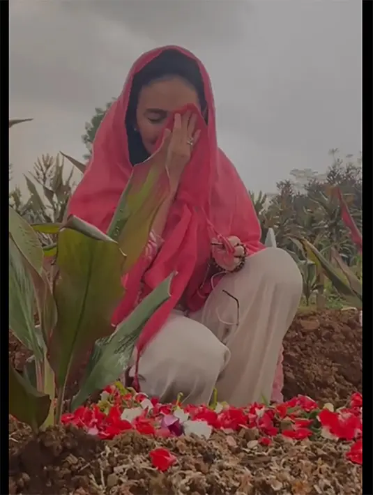 Rieke dan dua orang pria berpakaian putih tampak khusu memanjatkan doa di makam Nani Wijaya. [Foto; Instagram/riekediahp]