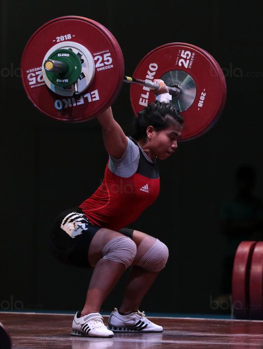Sri Wahyuni berkonsentrasi mengangkat beban saat turun pada kelas 48 kg di Hall A Arena PRJ, Jakarta, Rabu (11/2/2018). Sri Wahyuni meraih medali emas dengan total angkatan 187 kg. (Bola.com/Nicklas Hanoatubun)