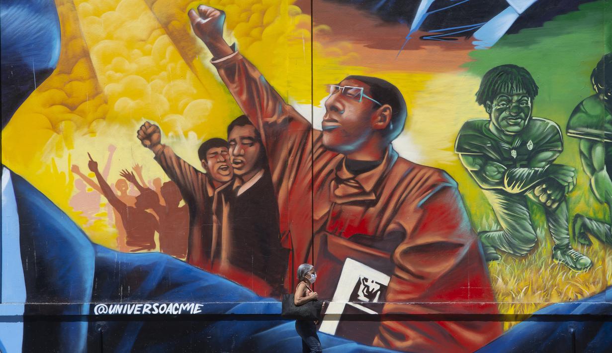 Seorang wanita melewati mural Sonhos de Liberdade karya seniman Acme, yang menghormati para pemimpin perjuangan untuk kesetaraan ras, di distrik seni Porto di Rio de Janeiro, 17 November 2021. Brasil menyambut Hari Kesadaran Kulit Hitam yang diperingati setiap 20 November. (AP Photo/Bruna Prado)