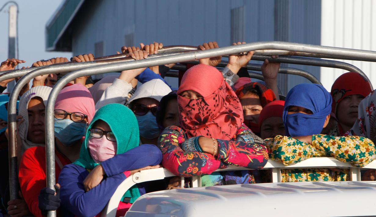Para pekerja menaiki mobil bak terbuka sebagai transportasi harian mereka pulang ke rumah dari tempat kerja di sebuah pabrik di dekat desa Trapang Anchanh, di luar Phnom Penh, Kamboja (27/10). (AP Photo/Heng Sinith)