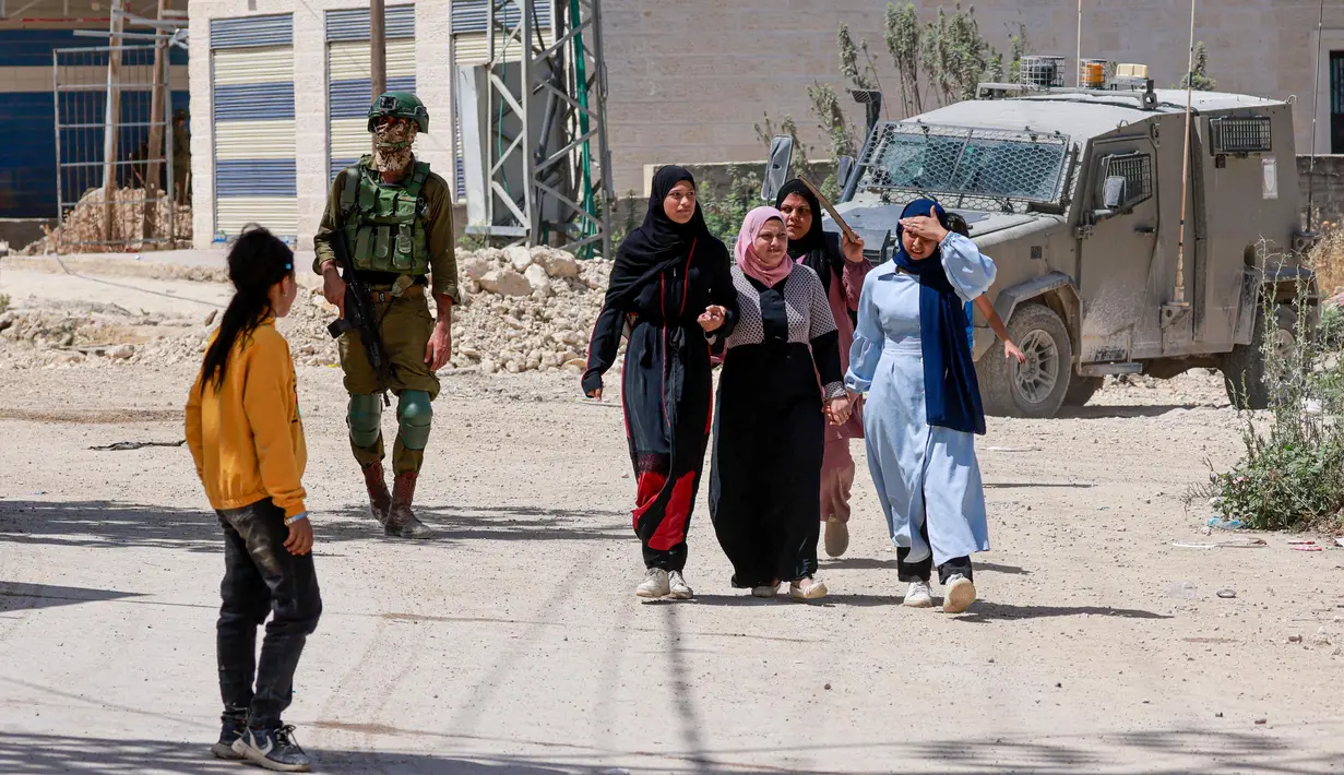 Dengan ketat, militer Israel mengawasi warga Palestina yang mengungsi meninggakan kamp pengungsi Tulkarem. (Jaafar ASHTIYEH/AFP)