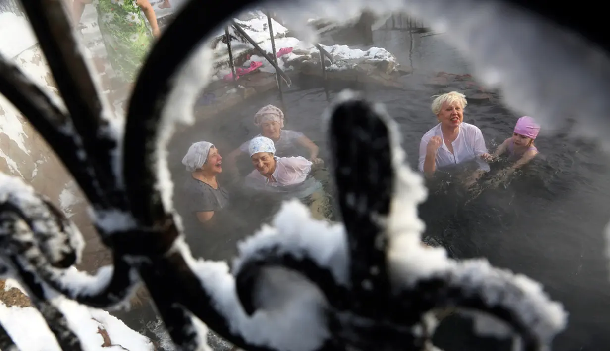 Orang-orang mandi dalam air selama perayaan Epiphany saat suhu turun menjadi sekitar -18 derajat (-0,4 derajat Fahrenheit) di dekat Biara Achairsky, luar Kota Omsk, Siberia, Rusia, Jumat (19/1/2024). (AP Photo/Evgeniy Sofiychuk)