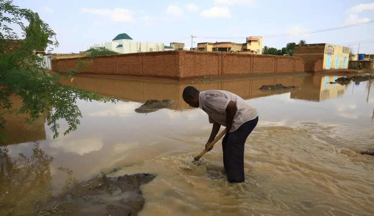 Seorang pria bekerja di tengah genangan banjir di Khartoum, Sudan (3/8/2020). Sudan dilanda banjir baru-baru ini akibat hujan lebat. (Xinhua/Mohamed Khidir)