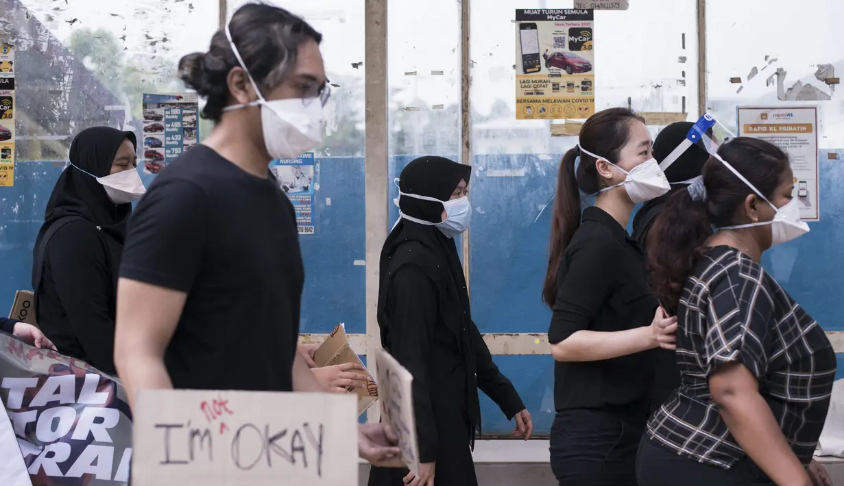 Dokter kontrak memegang plakat saat berpartisipasi dalam aksi mogok di Rumah Sakit Sungai Buloh di Selangor, Malaysia, Senin (26/7/2021). Mereka menuntut kondisi yang lebih baik di tengah pandemi virus Corona (COVID-19) yang makin melonjak. (AFP/Arif Kartono)