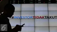 Pengunjung melintas di bawah layar bertuliskan #investor tidak takut di Bursa Efek Indonesia, Jakarta, Senin (18/1). Direktur utama BEI Tito menjelaskan tidak terjadi pengaruh besar pasca teror terhadap perdagangan di BEI. (Liputan6.com/Angga Yuniar)