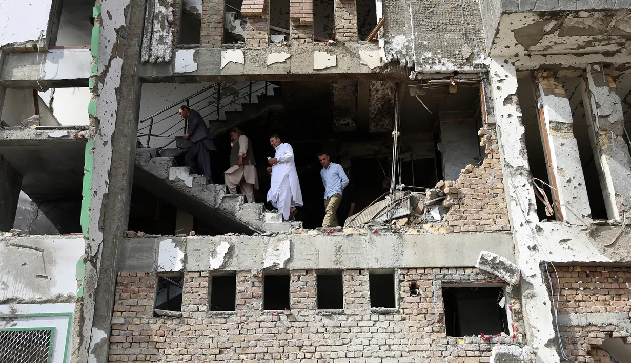 Warga berjalan dalam kantor pemenangan calon presiden Afghanistan Amrullah Saleh usai serangan bom, Kabul, Senin (29/7/2019). Juru bicara kepolisian Kabul, Ferdous Faramarz mengatakan serangan itu diprediksi bom mobil bunuh diri. (AP Photo/Rahmat Gul)
