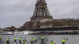 Peserta menyeberangi sungai Seine dekat menara Eiffel selama Nautic Paddle Race di Paris, Minggu (9/12). Sekitar 800 orang mengikuti lomba dayung sambil berdiri terbesar di dunia sejauh 11 km dengan pemandangan kota Paris. (Lucas BARIOULET/AFP)