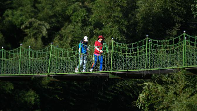 Wisatawan berjalan di sebuah jembatan gantung di Desa Luci, Kota Fuchunjiang, Tonglu, China, 6 September 2020. Pengunjung dapat mencicipi kehidupan pedesaan yang tenang tanpa hiruk pikuk di Kota Fuchunjiang dengan desa-desa berpemandangan indah dan objek wisata populer. (Xinhua/Huang Zongzhi)