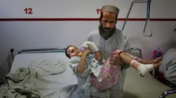 Ismatullah membawa putranya Eimal (9) yang kehilangan mata kanan dan beberapa jari tangannya dalam ledakan ranjau darat di Pusat Bedah Darurat untuk Korban Perang Sipil di Kabul, Afghanistan, Kamis (12/12/2019). (AP Photo/Altaf Qadri)