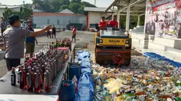 Petugas dengan alat berat menghancurkan botol minuman keras (miras) saat pemusnahan Miras dan barang bukti narkotika di Mapolrestabes Semarang, Jumat (20/12/2019). Pemusnahan barang bukti narkoba berupa sabu, inex dan pil koplo serta 5450 botol dan 140 liter ciu. (Liputan6.com/Gholib)