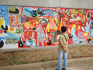 Warga melihat mural yang menghiasi tembok dalam acara Mural Cikini Project #1 di Taman Plaza Teater Besar, Taman Ismail Marzuki, Jakarta, Jumat (23/8/2019). Project #1/Mural Cikini yang diikuti oleh 4 seniman digelar dalam rangka menata estetika ruang publik. (Liputan6.com/Faizal Fanani)