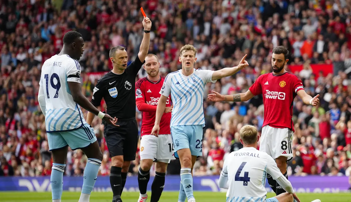 Wasit, Stuart Attwell (dua kiri), memberikan kartu merah kepada pemain Joe Worall, setelah dirinya melanggar pemain MU, Bruno Fernandes (kanan), di depan gawang Nottingham Forrest dalam pertandingan pekan ketiga Liga Inggris 2023/2024 yang berlangsung di Old Trafford, Manchester, Inggris, Sabtu (26/8/2023). (AP Photo/Jon Super)