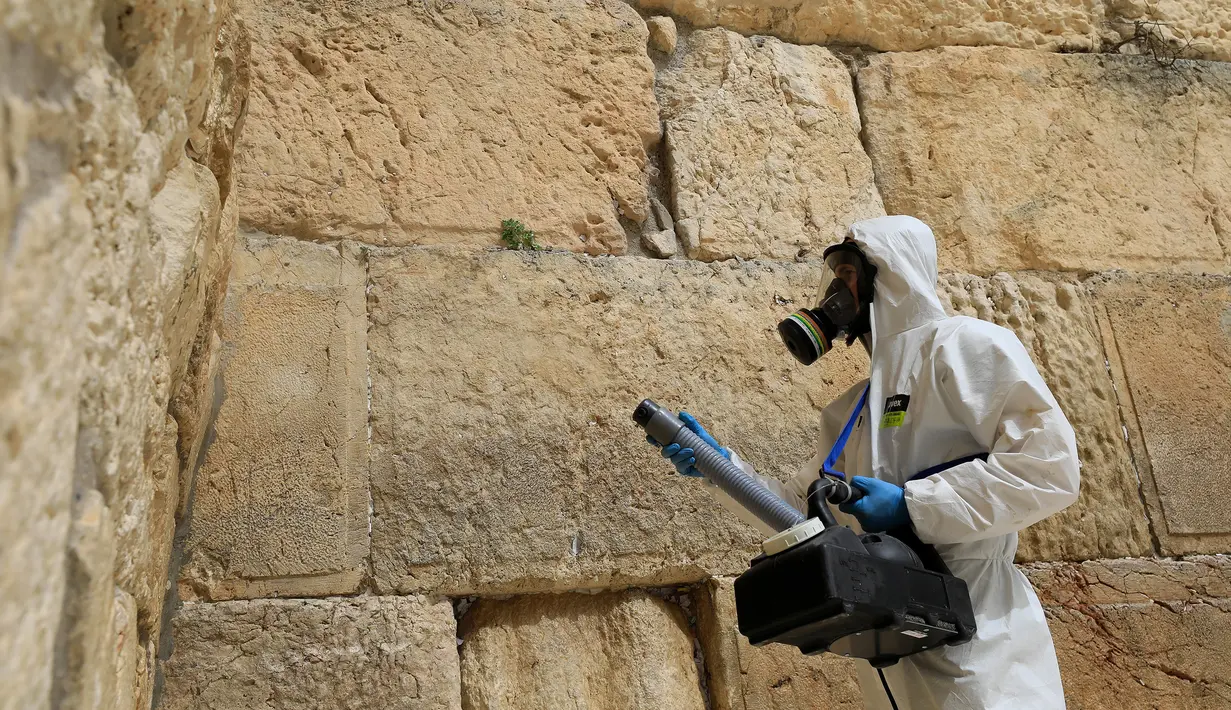 Seorang pekerja membersihkan Tembok Ratapan, situs paling suci di mana orang Yahudi dapat berdoa sebagai bagian dari langkah-langkah untuk mencegah penyebaran Covid-19 di Kota Tua Yerusalem (31/3/2020). (AFP/Emmanuel Dunand)