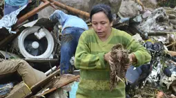 Seorang wanita membawa ayam hidup dari puing-puing setelah lereng bukit yang diguyur hujan runtuh menimpa rumah-rumah di Pereira, Kolombia, Selasa (8/2/2022). Hujan deras memicu tanah longsor yang menyapu daerah perumahan ini, menewaskan sedikitnya 14 orang dan melukai 35 lainnya. (AP Photo/Andres O