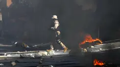 Polisi membersihkan jalan dari batu dan ban yang dibakar oleh pengunjuk rasa yang marah dengan meningkatnya kekerasan di lingkungan Lalue, Port-au-Prince, Haiti, Rabu (14/7/2021). Presiden Haiti Jovenel Moise dibunuh pada 7 Juli. (AP Photo/Fernando Llano)