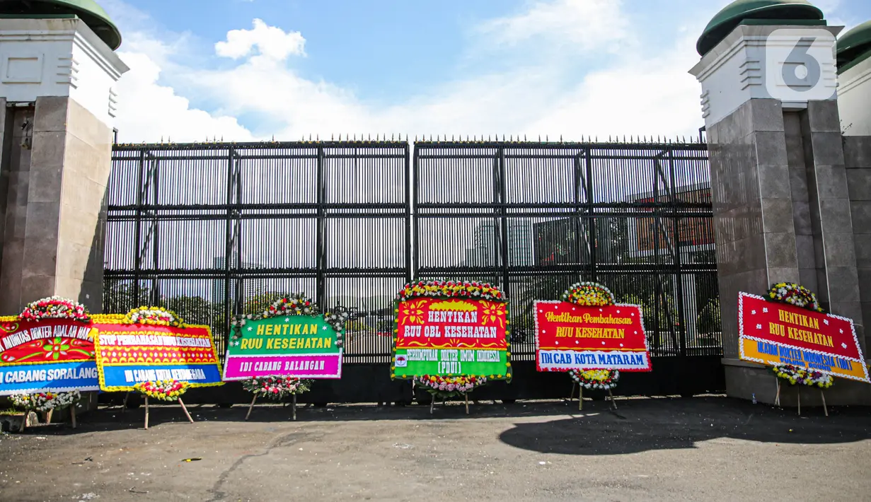Karangan bunga menolak RUU Kesehatan Omnibuslaw menghiasi depan gerbang Gedung DPR, Jakarta, Rabu (12/4/2023). (Liputan6.com/Faizal Fanani)