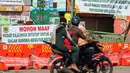 Warga melintasi pintu masuk kawasan Pasar Cileungsi yang dipenuhi spanduk penutupan, Kabupaten Bogor, Selasa (2/6/2020). Penutupan sementara kegiatan jual beli di Pasar Cileungsi terkait adanya tujuh pedagang yang positif terinfeksi virus COVID-19. (Liputan6.com/Helmi Fithriansyah)