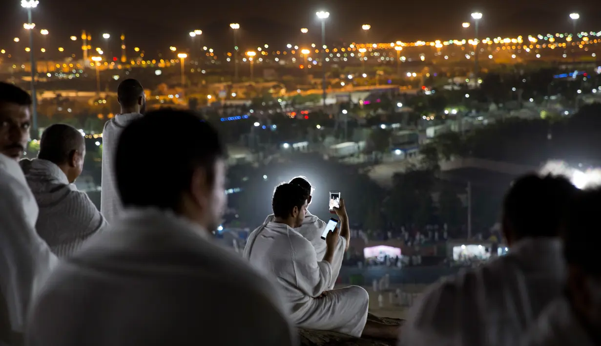 Jemaah calon haji mengabadikan gambar saat berada di Bukit Jabal Rahmah di luar kota suci Mekah, Arab Saudi (30/8). Bukit Jabal Rahmah dikenal sebagai bukit kasih sayang. (AP Photo / Khalil Hamra)