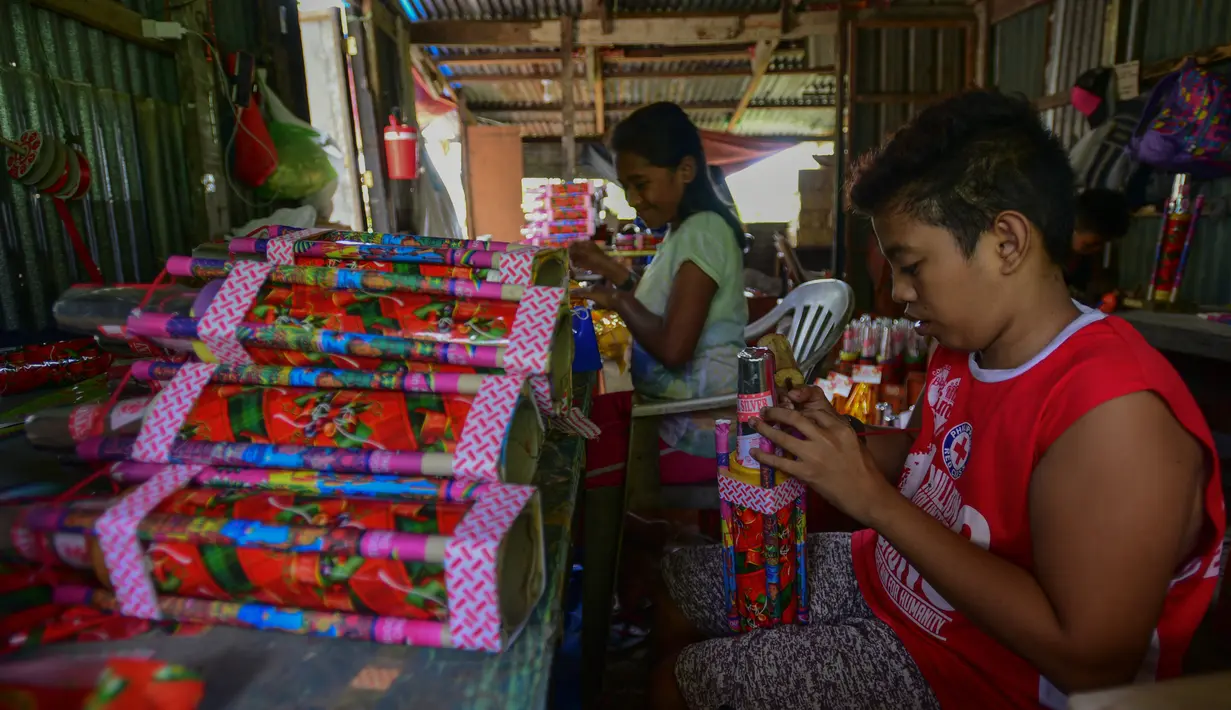 Para pekerja menyelesaikan pembuatan petasan di sebuah pabrik di Bocaue, Bulacan, Filipina, Jumat (27/12/2019). Petasan-petasan tersebut akan dijual untuk perayaan Tahun Baru 2020. (Maria TAN/AFP)