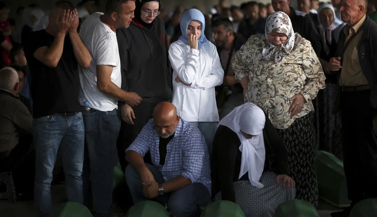 Pria dan wanita muslim berdoa dekat peti mati kerabat mereka yang menjadi korban genosida Srebrenica 1995 di Potocari, Bosnia, 8 Juli 2022. Sebanyak 50 jenazah korban genosida Srebrenica yang baru diidentifikasi, satu-satunya genosida yang diakui di Eropa sejak Perang Dunia II, tiba di Memorial Center di Potocari di mana mereka akan dimakamkan pada 11 Juli. (AP Photo/Armin Durgut)