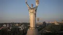 Para pekerja memasang lambang Ukraina pada perisai di tangan monumen tertinggi di negara itu, Monumen Tanah Air, setelah lambang Soviet dihapus, di Kiev, Ukraina, Minggu, 6 Agustus 2023. (AP Photo/Efrem Lukatsky)