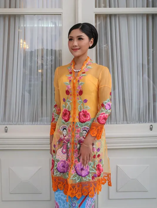 Erina Gudono mengenakan kebaya encim berwarna oranye. Kebaya ini memiliki detail manis berupa motif flora, dipadukan kain batik bernuansa biru muda sebagai rok. [Foto: Instagram/erinagudono]