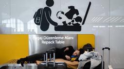 Penumpang yang terdampar menunggu di bandara Istanbul, di mana penerbangan dibatalkan karena badai salju dan hujan salju lebat, di Istanbul, Turki, pada 25 Januari 2022. Penutupan salah satu bandara tersibuk di Eropa ini akibat hantaman badai salju yang menghambat operasional. (Yasin AKGUL/AFP)