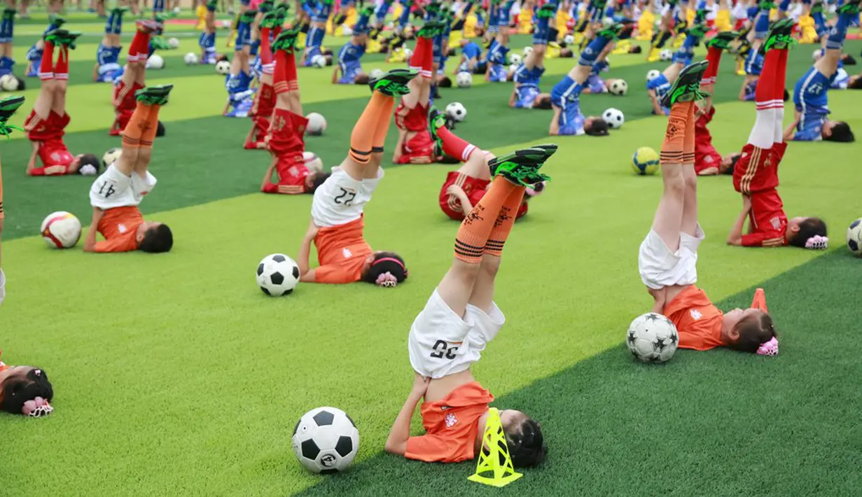 Para siswa beraksi dengan bola saat acara pembukaan sebuah turnamen sepak bola di Dalian, Liaoning, China, (16/7/2016). (Reuters)