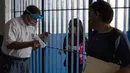 Seorang guru yang memakai pelindung wajah (kiri) berbicara dengan ibu siswa melalui gerbang Sekolah Menengah Umum "Tito Salas" selama hari pendaftaran tahun ajaran 2020-2021 di tengah pandemi virus corona, di Las Minas de Baruta, Caracas, pada 7 Oktober 2020. (Cristian Hernandez/AFP)
