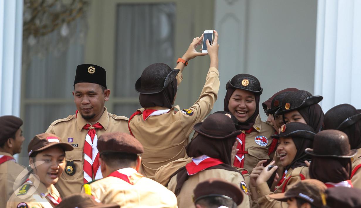 Seorang wanita dari delegasi gerakan Pramuka Indonesia tampak berselfie ria di Halaman Istana Merdeka, Jakarta, Jumat (24/7/2015). Presiden Jokowi juga menghadiri acara pelepasan 462 kontingen Pramuka Indonesia ke jepang. (Liputan6.com/Faizal Fanani)