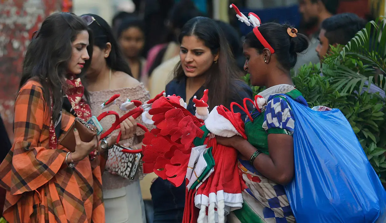 Tiga wanita membeli pernak-pernik Natal di sebuah pasar di Mumbai, India (14/12). Meskipun umat Kristen hanya sekitar 2 persen dari populasi India, Suasana kemeriahan Natal sudah dirasakan. (AP Photo / Rafiq Maqbool)