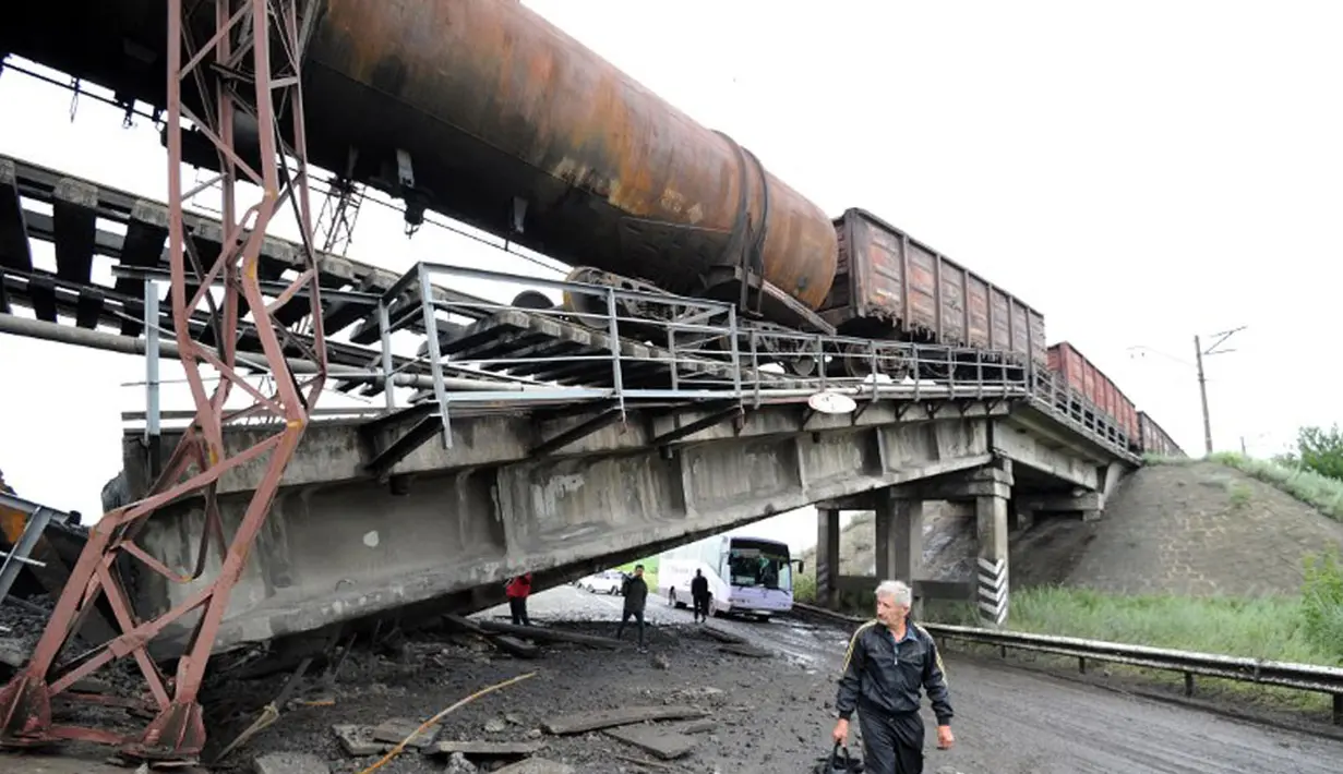  Meski terlihat berbahaya, beberapa orang dan pengemudi nekad melintasi kolong jembatan kereta yang rusak di dekat desa Novobakhmutivka, 30 km sebelah utara Donetsk, Ukraina, (8/7/2014). (AFP PHOTO/Dominique Faget)