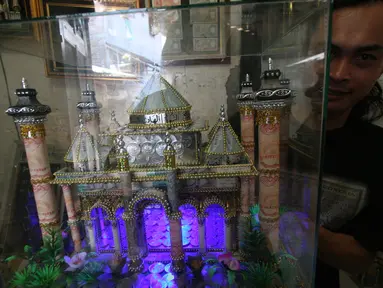 Seorang perajin, Albani, menunjukkan mahar pernikahan berbentuk miniatur masjid, di dusun Jotowang, Yogyakarta, Rabu (15/6). Pada Ramadan, pemesanan miniatur masjid berbahan dasar uang pecahan rupiah itu mengalami peningkatan. (Liputan6.com/Boy Harjanto)