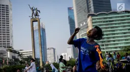 Seorang pria melakukan atraksi menelan api di area Car Free Day kawasan MH Thamrin, Jakarta, Minggu (4/6). Pria yang tergabung dalam kelompok seniman Kuda Lumping tersebut melakukan aksi berbahaya untuk mencari nafkah. (Liputan6.com/Faizal Fanani)