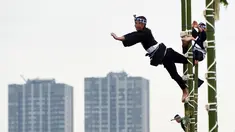 Para pemadam kebakaran berpakaian tradisonal menunjukan keahliannya menyeimbangkan tubuh di atas puncak bambu saat perayaan Tahun Baru di Tokyo, Jepang, Jumat (6/1). Atraksi ini mereka persembahkan untuk perayaan Tahun Baru. (Toshifumi KITAMURA/AFP)
