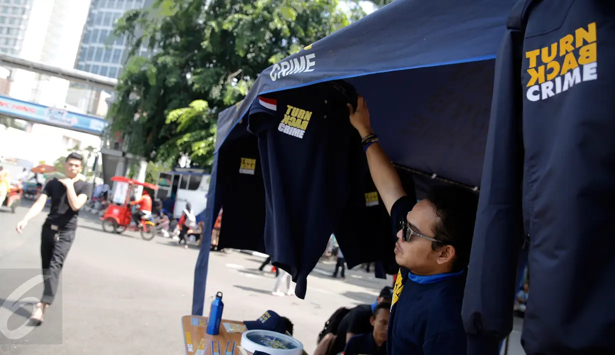 Penjual saat menjual baran dagangannya yang bertulisan "Turn Back Crime" saat Car Free Day kawasan Bunderan HI, Jakarta (13/3). Penggunaan merk 'Turn Back Crime' bertujuan untuk kampanye waspada tindak kejahatan. (Liputan6.com/Faizal Fanani)