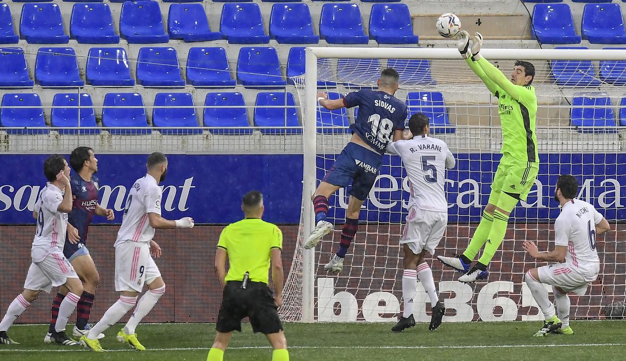 Aksi dari kiper Real Madrid, Thibaut Courtois menepis bola serangan dari pemain Huesca. (Foto: AP/Alvaro Barrientos)