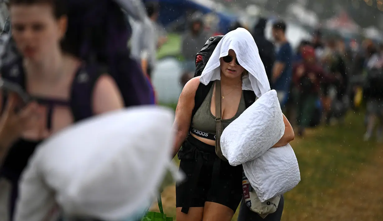 Ribuan penonton Glastonbury diguyur hujan sore ini saat mereka bersiap-siap untuk berkemah demi menyaksikan penampilan Elton John, Arctic Monkeys, dan Guns N' Roses dalam acara musik spektakuler selama lima hari. (Photo by Oli SCARFF / AFP)