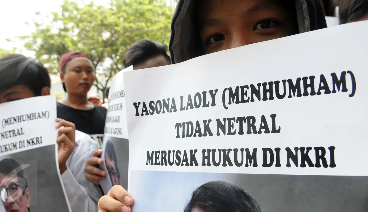 Salah satu massa menutup wajahnya dengan poster Menteri Yasonna Laoly saat unjuk rasa di Kantor Kemenkumham Jakarta, Rabu (30/12). Aksi puluhan orang itu mempersoalkan legalitas kepengurusan PPP yang terbagi menjadi dua kubu. (Liputan6.com/Helmi Afandi)