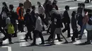 Orang-orang mengenakan masker untuk membantu mencegah penyebaran virus corona berjalan di sepanjang penyeberangan pejalan kaki di Tokyo (21/4/2021). Ibukota Jepang mengonfirmasi lebih dari 840 kasus virus corona baru pada hari Rabu. (AP Photo/Eugene Hoshiko)