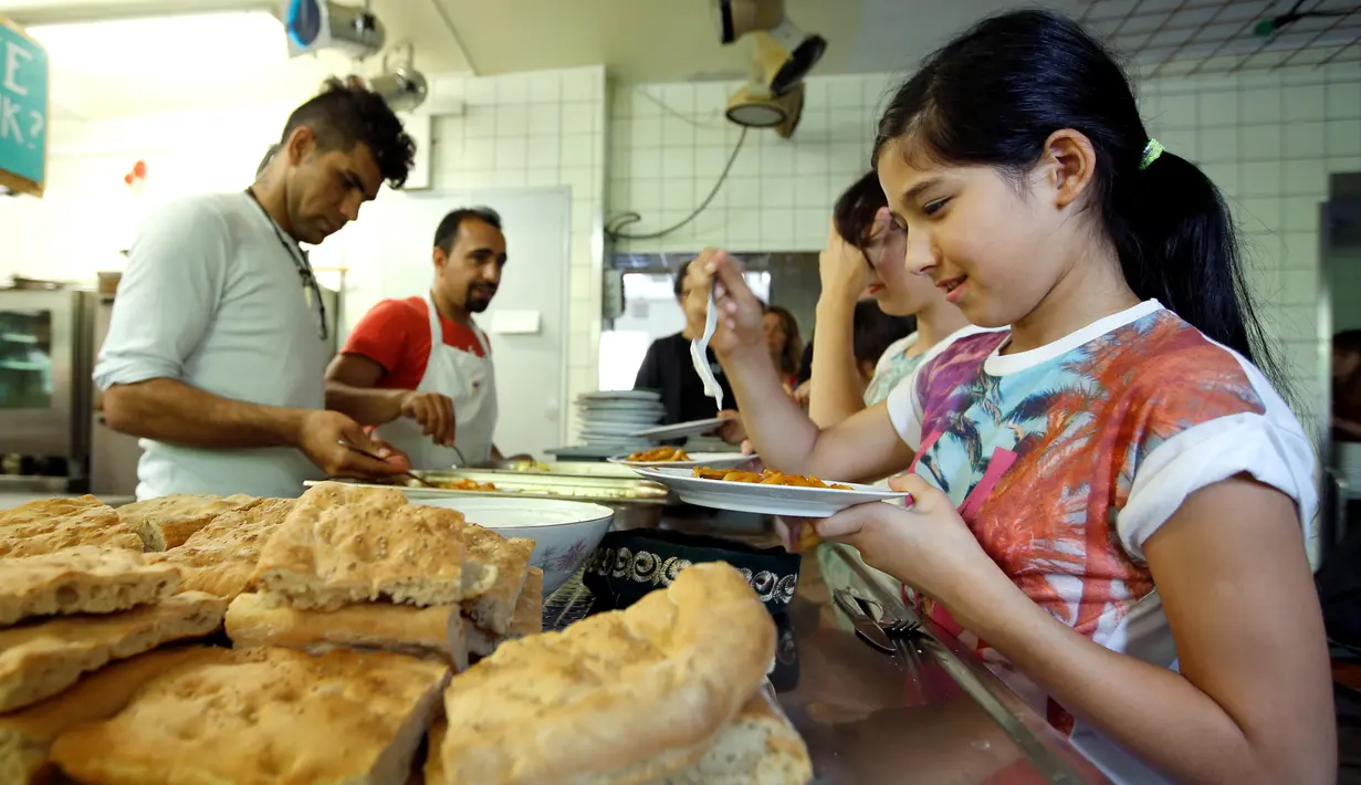 Para imigran dan tamu memilih makanannya saat berada di ruangan makan "Grandhotel Cosmopolis", di Augsburg, Jerman, (27/7). Hotel ini dapat menampung sekitar 65 imigran dan wisatawan dari seluruh dunia. (REUTERS/Michaela Rehle)