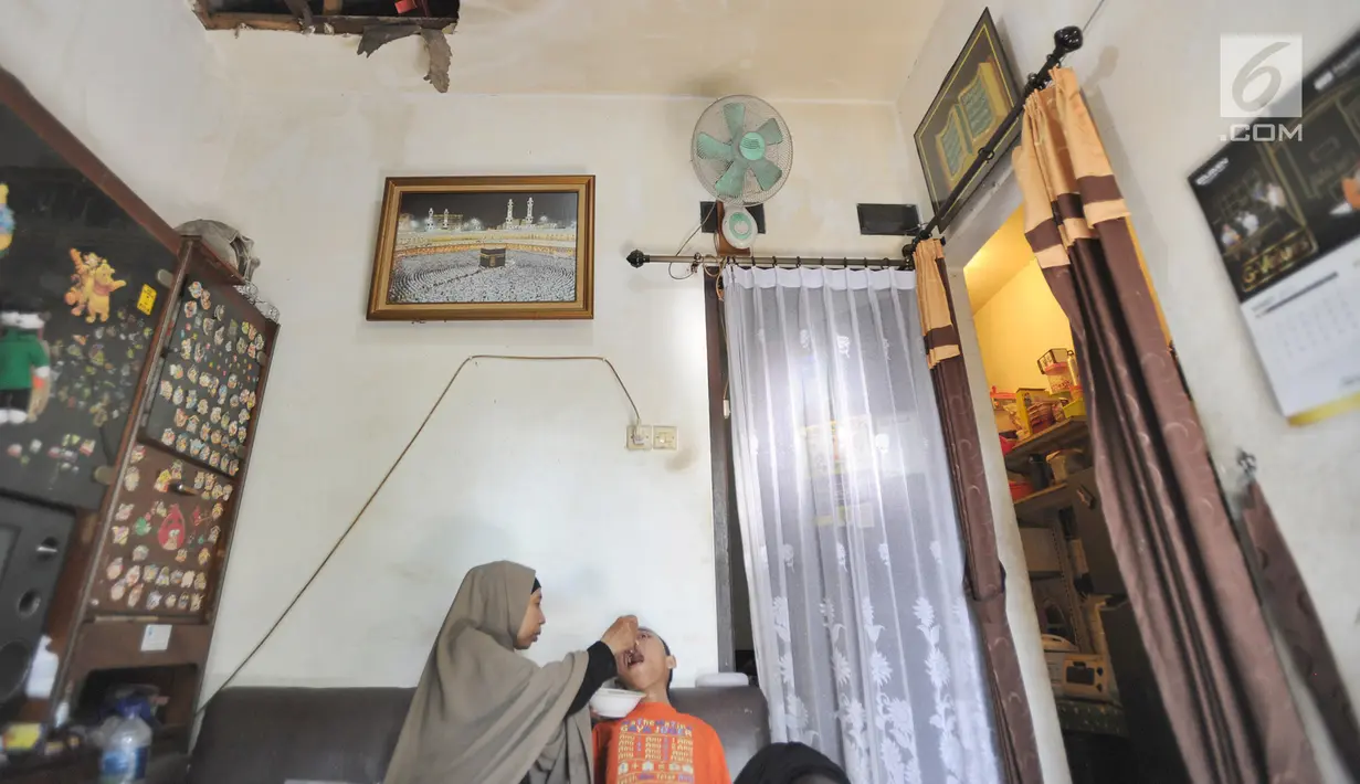 Setiap pagi, sang ibu memandikan dan memakaikan seragam SMP, pakaian kebanggaan Fauzan Akmal Maulana. Lalu, setelah disuapi sarapan oleh sang ibu, Fauzan digendong sang ibu menuju sekolah. (merdeka.com/Arie Basuki)