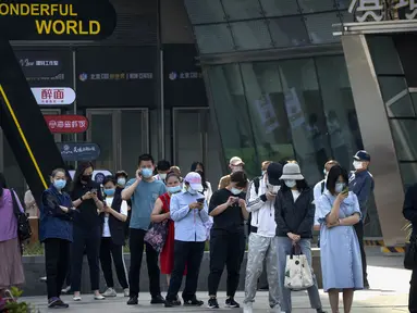 Orang-orang yang memakai masker berbaris untuk tes COVID-19 pada hari ketiga berturut-turut dari pengujian virus corona massal di Beijing, Kamis (5/5/2022). Ibu kota China Beijing pada Kamis (5/5) mulai melonggarkan aturan karantina untuk kedatangan dari luar negeri. (AP Photo/Mark Schiefelbein)