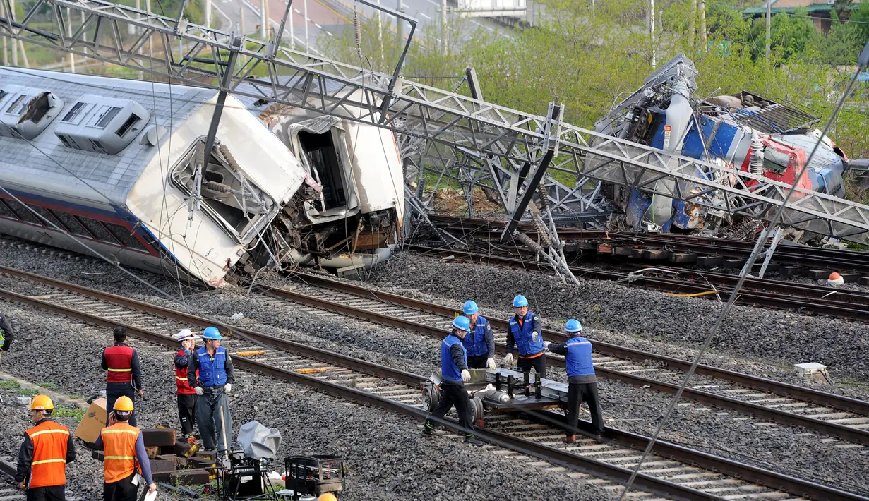 Petugas berusaha mengevakuasi sebuah kereta penumpang yang tergelincir di kota pelabuhan selatan Yeosu, Korea Selatan, Jumat (22/4). Akibat kecelakaan itu masinis tewas, sementara delapan penumpang mengalami luka-luka. (Hwang Hee-kyu/News1 via REUTERS)