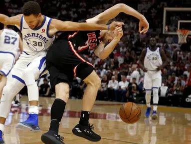 Pebasket Golden State Warriors, Stephen Curry, berebut bola dengan pebasket Miami Heat, Goran Dragic, pada laga NBA di American Airlines Arena, Miami, Senin (4/12/2017). Warriors menang 123-95 atas Heat. (AP/Joe Skipper)