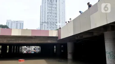 Warga melihat kondisi underpass Kemayoran yang masih terendam bajir di Jakarta Pusat, Minggu (26/1/2020). Banjir yang terjadi sejak Jumat (24/1) lalu hingga kini belum surut. (merdeka.com/Iqbal S Nugroho)