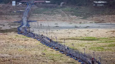 Orang-orang melintas di atas jembatan terapung sepanjang 300 meter yang melintasi Sungai Citarum yang mengering di Cihampelas, Jawa Barat pada 4 Oktober 2023. (Timur MATAHARI/AFP)