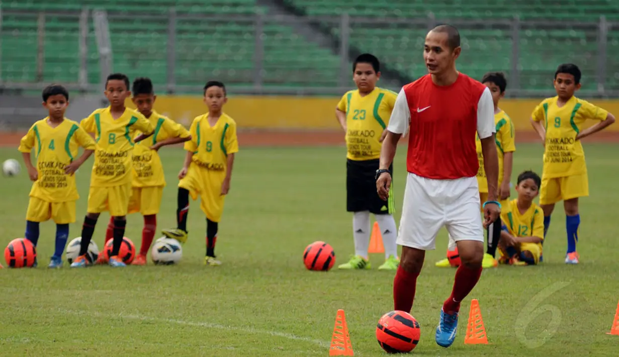Mantan pemain Timnas Indonesia, Kurniawan Dwi Yulianto memberikan contoh teknik memainkan si kulit bundar kepada anak-anak di Stadion GBK Jakarta, (6/6/2014). (Liputan6.com/Helmi Fithriansyah)